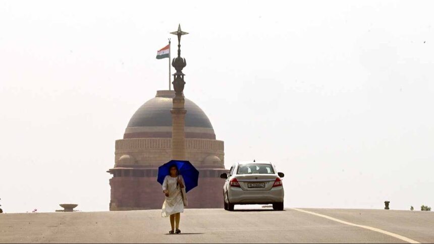 भीषण गर्मी से बचने के लिए एक महिला छतरी लेकर रायसीना हिल्स पर चलती हुई. (सभी फोटोः एपी)