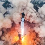 aerial view of a huge rocket launching from a seaside pad, creating a giant cloud of exhaust and dust