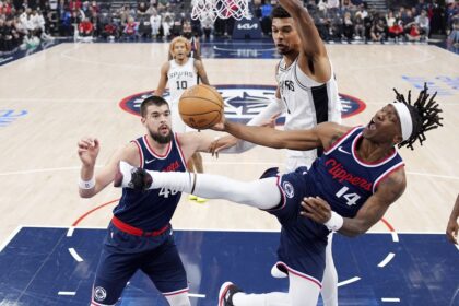 Los Angeles Clippers guard Terance Mann, right, shoots as San Antonio Spurs center Victor Wembanyama, top, defends and center Ivica Zubac watches during the first half of an NBA basketball game, Monday, Nov. 4, 2024, in Inglewood, Calif. (AP Photo/Mark J. Terrill)