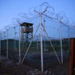 Chain link fence and concertina wire surrounds a deserted guard tower within Joint Task Force Guantanamo's Camp Delta at t...