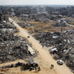 Palestinians walk past the rubble of buildings destroyed during the Israeli offensive in Rafah